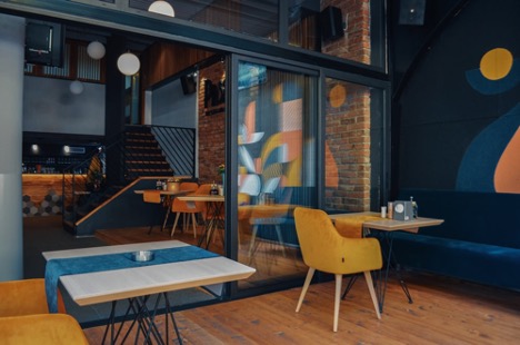 Modern cafe interior with yellow chairs and mural